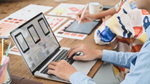 Cropped image of two people is using a computer laptop with an interface icon.